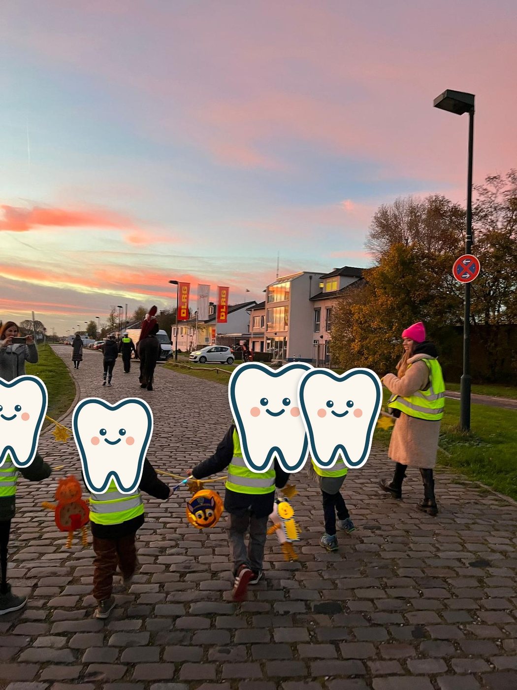 Laternenumzug im Abendrot – die Kinder von hinten, mit Warnwesten und Laternen