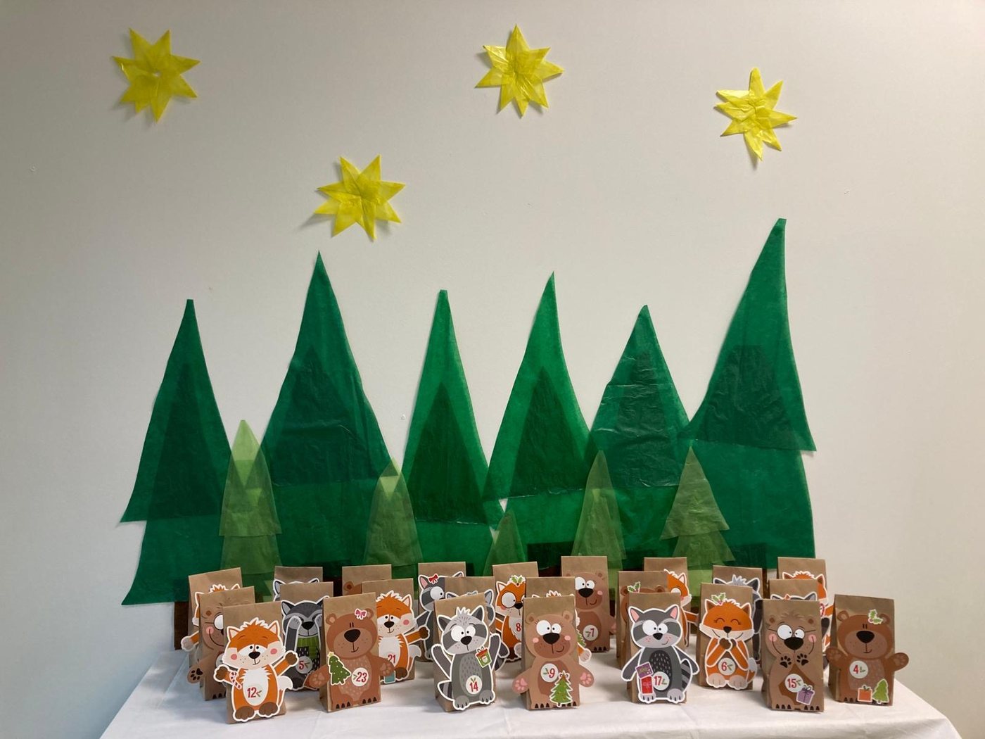 Adventskalender aus Tüten mit Waldtieren vor Papiertannen